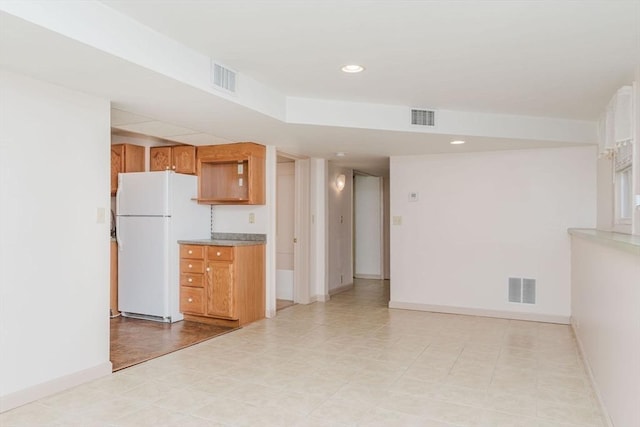 kitchen with visible vents, brown cabinets, and freestanding refrigerator