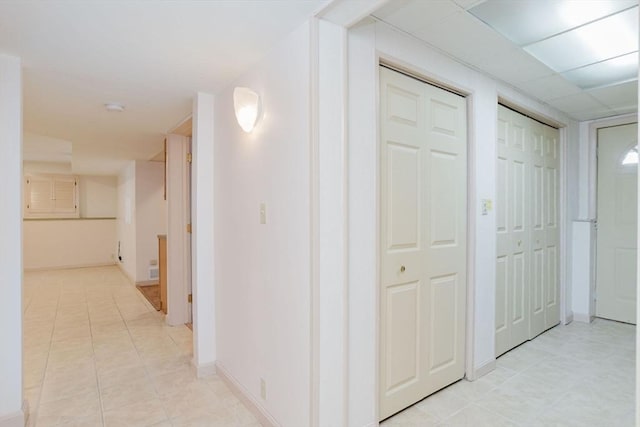 corridor featuring light tile patterned floors and baseboards