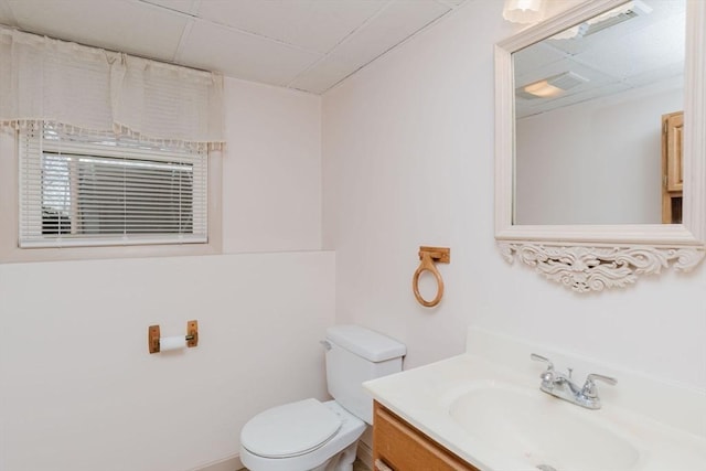 half bathroom featuring vanity, toilet, and a paneled ceiling