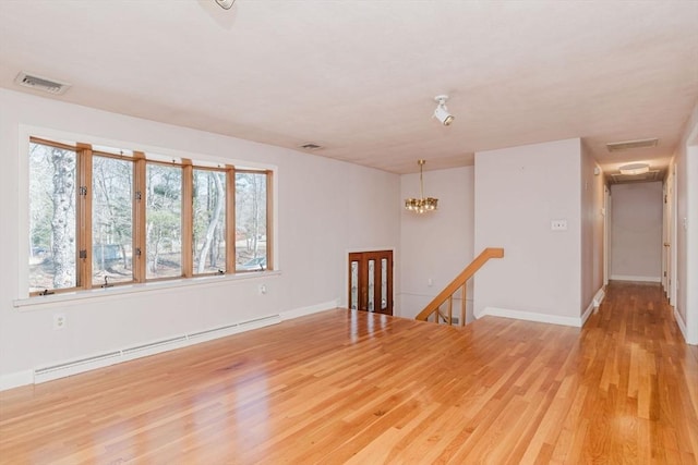 empty room with a baseboard radiator, visible vents, wood finished floors, and a chandelier