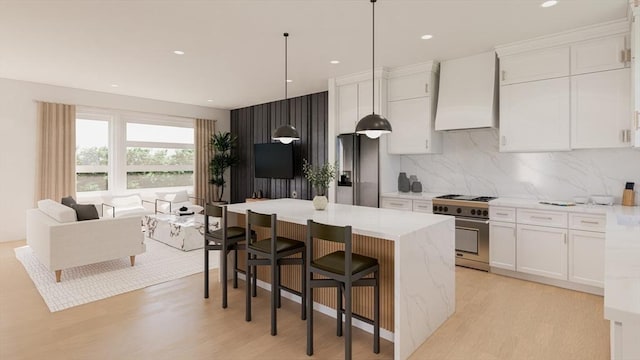 9 Franklin Unit A, Salem, MA 01970 - kitchen with stainless steel appliances, custom exhaust hood, white cabinetry, decorative backsplash, and a center island