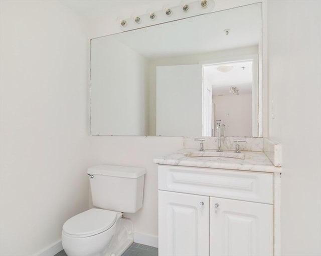 half bathroom featuring toilet, baseboards, vanity, and tile patterned floors