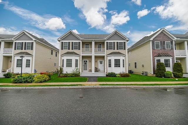 multi unit property featuring a balcony, cooling unit, and a front yard