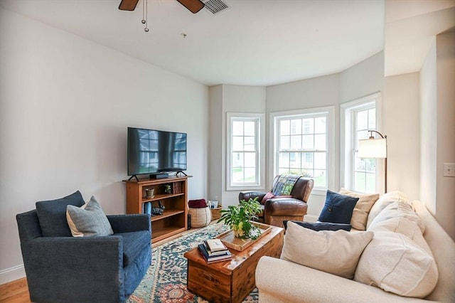 living room with ceiling fan, baseboards, and wood finished floors