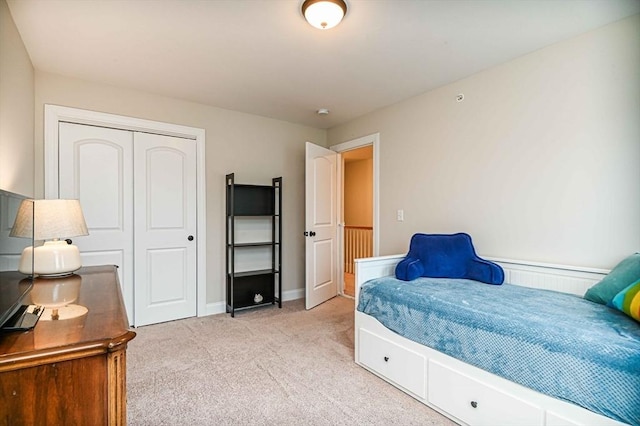 bedroom with light carpet, a closet, and baseboards