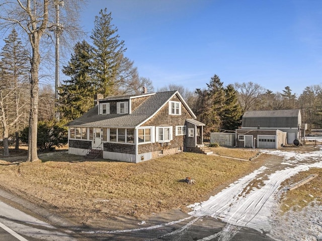 view of front of home featuring covered porch, a garage, and an outbuilding