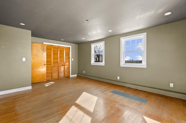 unfurnished bedroom featuring light hardwood / wood-style flooring and a baseboard radiator