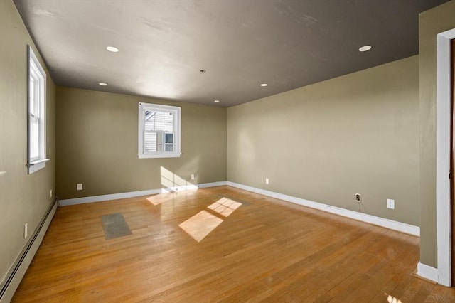 empty room with a baseboard heating unit and light hardwood / wood-style floors