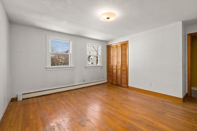 spare room featuring baseboard heating and hardwood / wood-style flooring