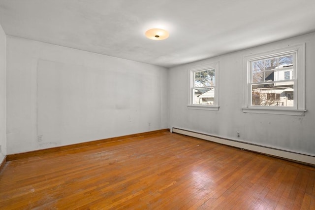 empty room featuring baseboard heating and wood-type flooring