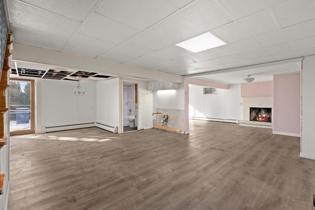 basement featuring a baseboard radiator, hardwood / wood-style floors, and a brick fireplace