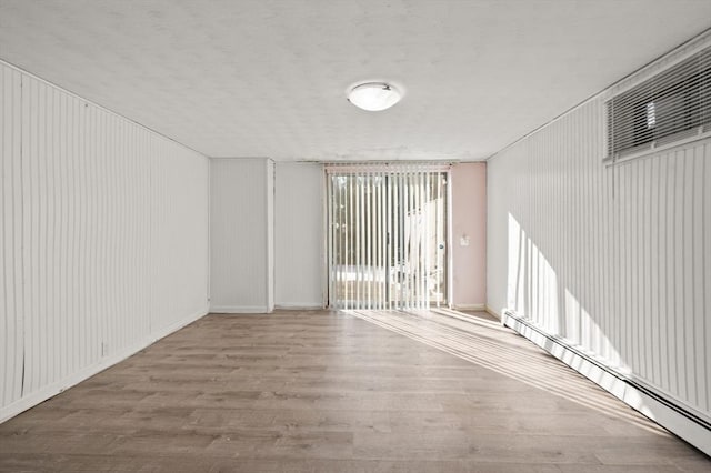 empty room featuring hardwood / wood-style flooring and a baseboard heating unit