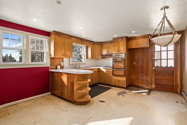 kitchen featuring sink, white gas stovetop, kitchen peninsula, pendant lighting, and wall oven