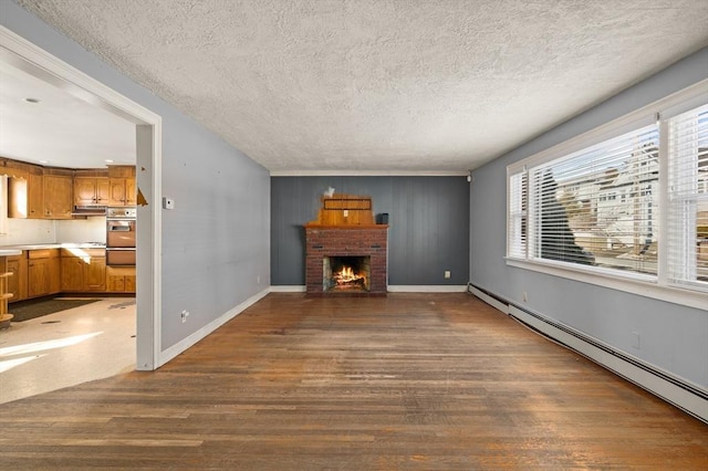 unfurnished living room featuring a brick fireplace, dark hardwood / wood-style floors, a textured ceiling, and baseboard heating