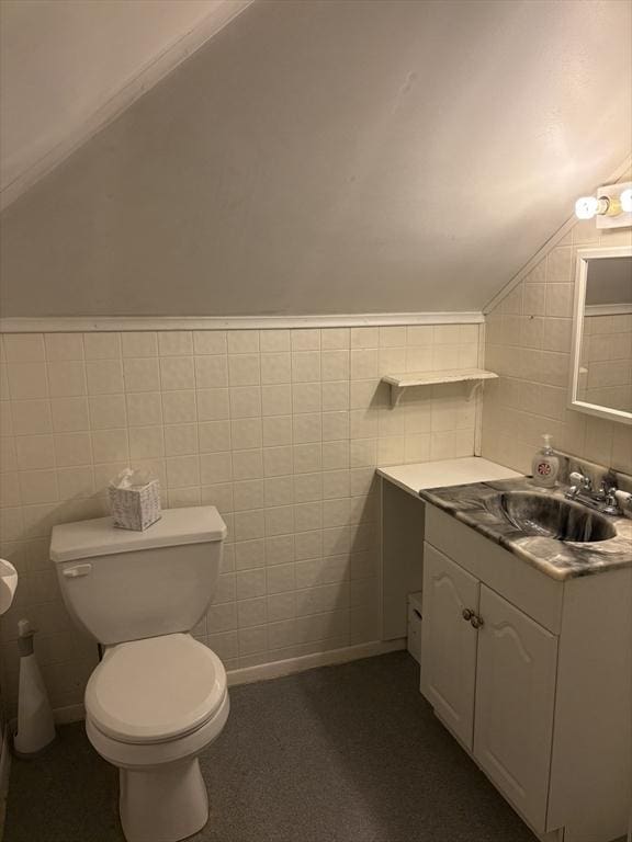 bathroom with toilet, tile walls, lofted ceiling, and vanity