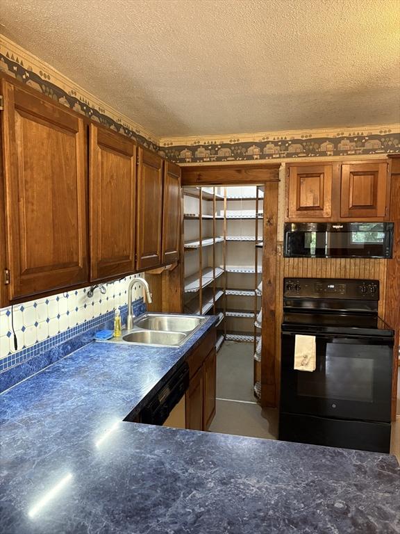kitchen with brown cabinets, a textured ceiling, a sink, and black appliances
