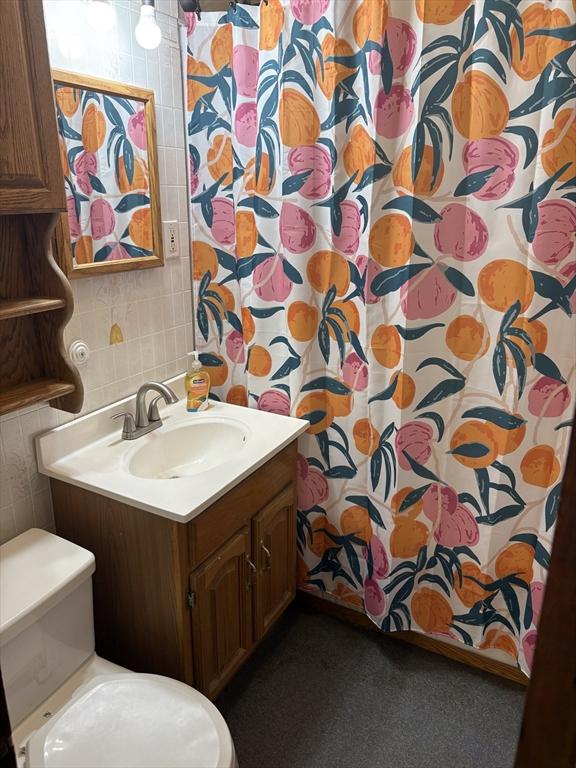 full bath featuring vanity, curtained shower, toilet, tile walls, and backsplash