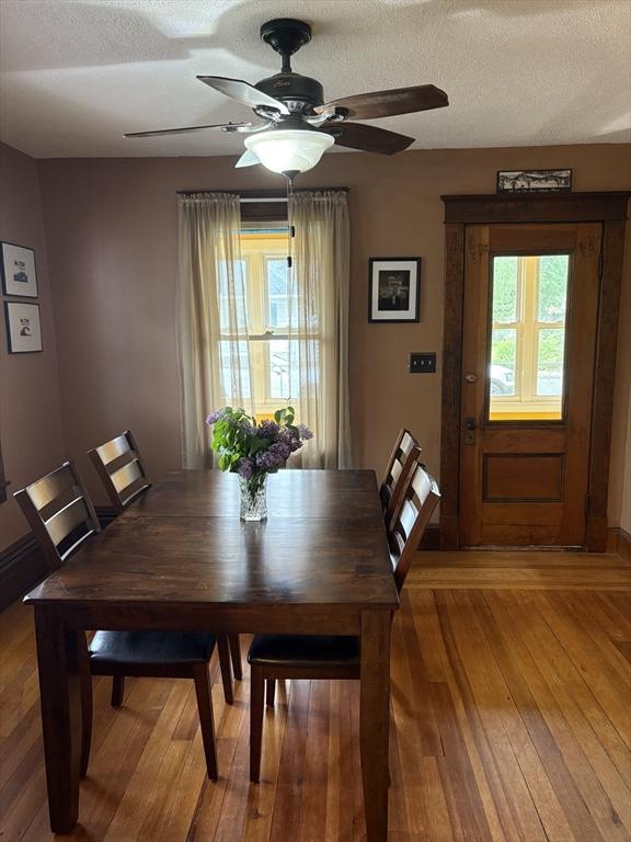 dining space with light wood-type flooring, a textured ceiling, ceiling fan, and baseboards