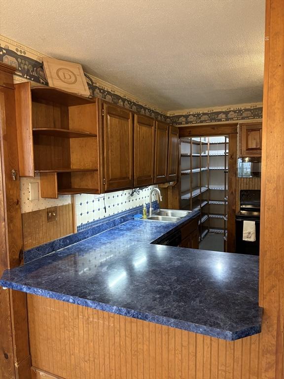 kitchen featuring open shelves, black range with electric cooktop, dark countertops, a textured ceiling, and a sink