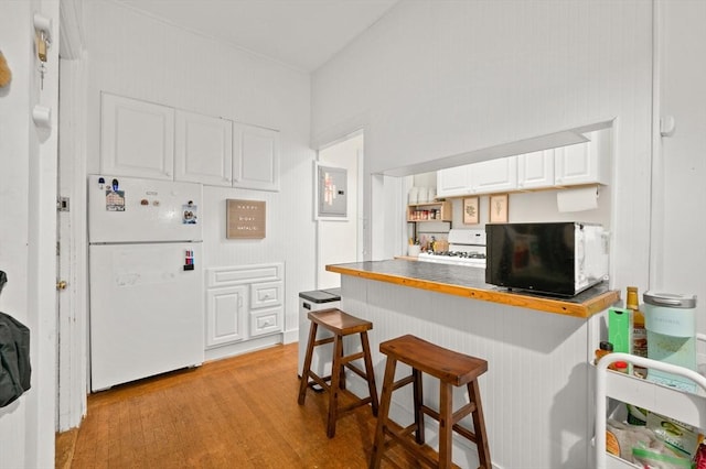 293-295 Commonwealth Ave Unit 3B, Boston, MA 02115 - kitchen with white appliances, white cabinets, a breakfast bar, light wood finished floors, and electric panel