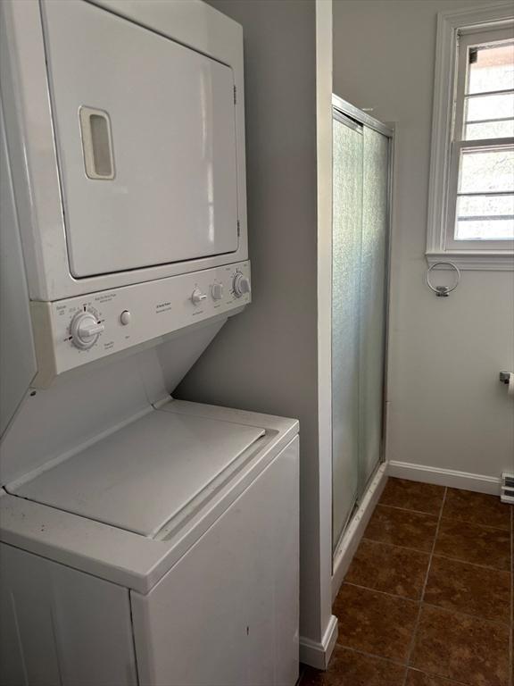 83 Partridge Valley Rd, Yarmouth, MA 02673 - washroom featuring estacked washer and dryer, baseboards, and dark tile patterned flooring