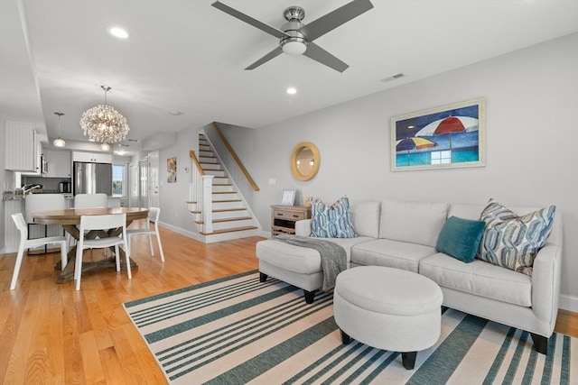 35 Liberty St, Salisbury, MA 01952 - living room featuring stairway, a chandelier, baseboards, a ceiling fan, and light wood-type flooring