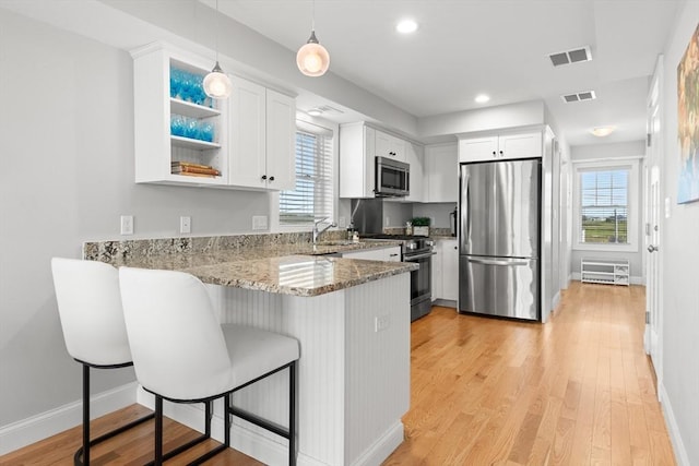 35 Liberty St, Salisbury, MA 01952 - kitchen with stainless steel appliances, a peninsula, light stone countertops, white cabinets, and baseboards