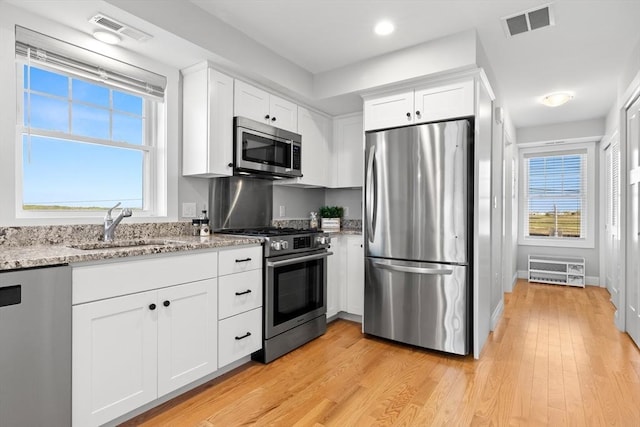 35 Liberty St, Salisbury, MA 01952 - kitchen featuring stainless steel appliances, a sink, white cabinetry, light stone counters, and light wood-style floors