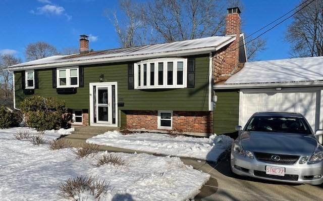 split foyer home featuring a garage, brick siding, and a chimney