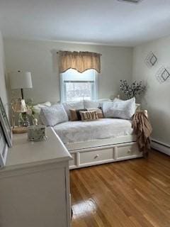 bedroom with baseboard heating and wood finished floors