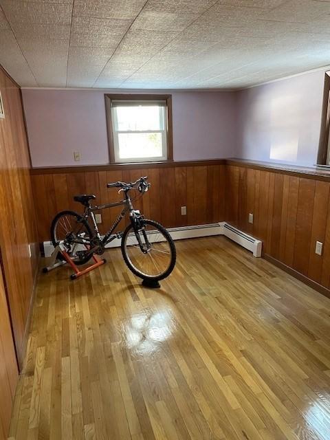 interior space with a wainscoted wall, wooden walls, a textured ceiling, and light wood-style floors