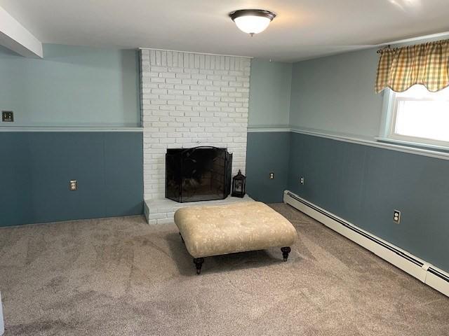 living area with a baseboard heating unit, carpet, and a fireplace