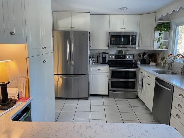 kitchen with white cabinets, appliances with stainless steel finishes, open shelves, and a sink