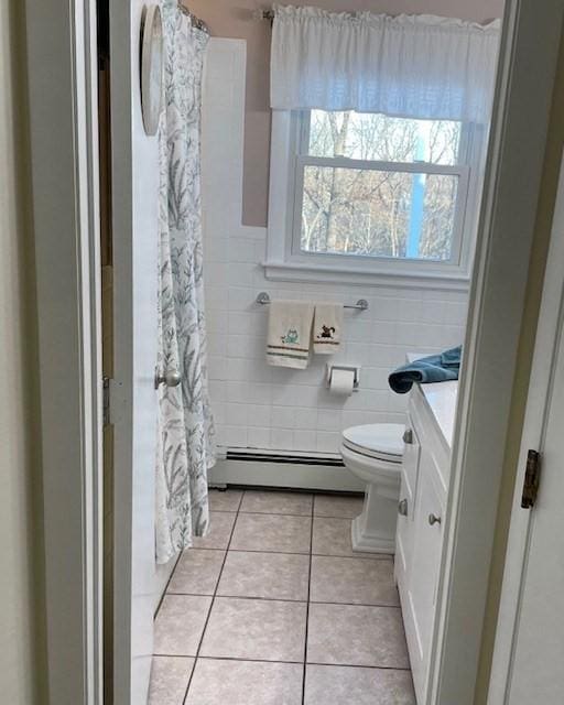 full bathroom with tile walls, toilet, baseboard heating, vanity, and tile patterned flooring