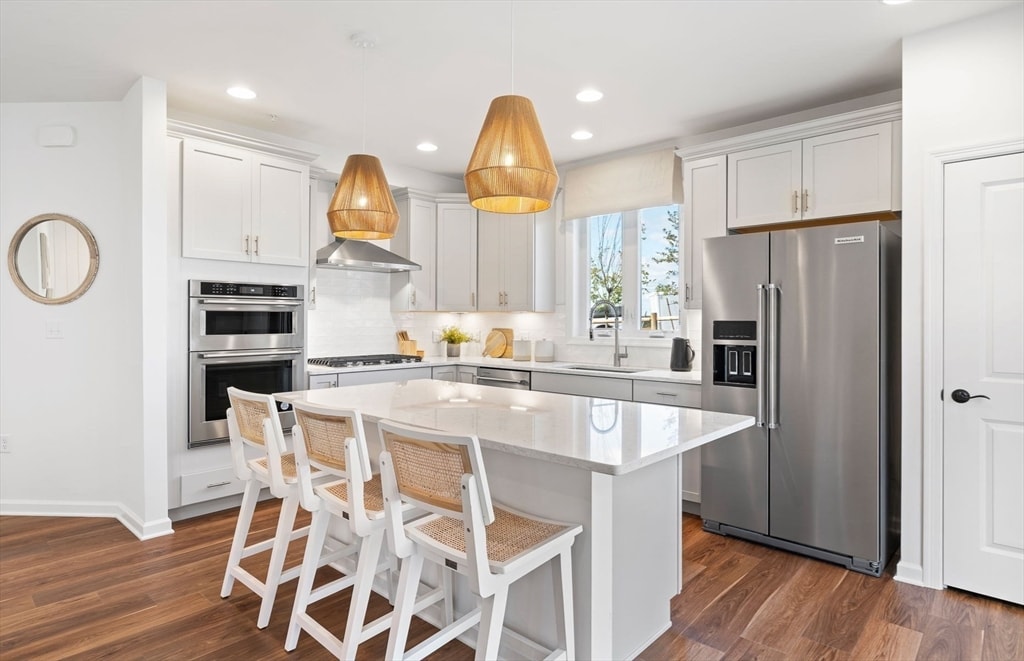 kitchen with white cabinetry, sink, a center island, hanging light fixtures, and appliances with stainless steel finishes