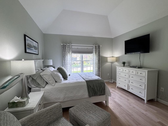 bedroom with vaulted ceiling, light wood finished floors, and baseboards