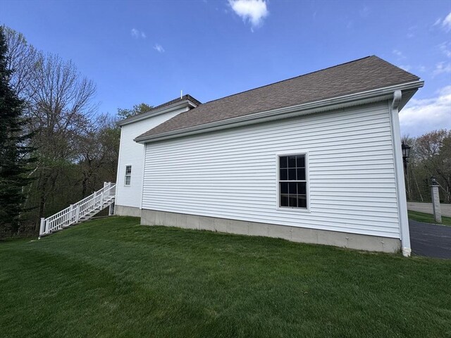 view of home's exterior featuring a lawn and a shingled roof