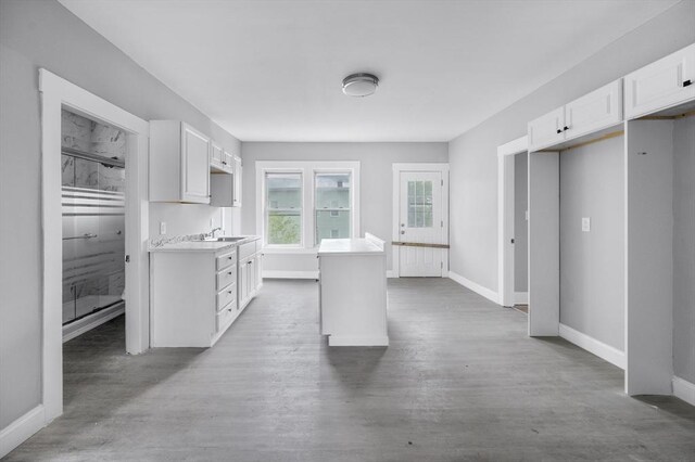 14-18 Florence St, Leominster, MA 01453 - kitchen with a kitchen island, white cabinetry, a sink, baseboards, and light countertops