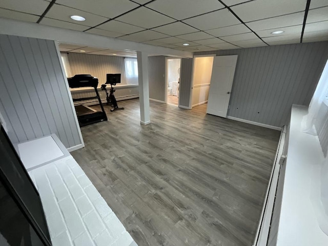 basement with wood walls, a drop ceiling, and hardwood / wood-style flooring