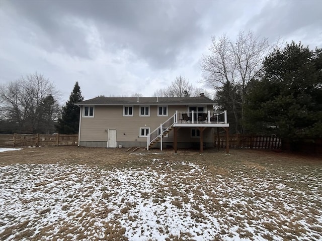 snow covered back of property with a wooden deck