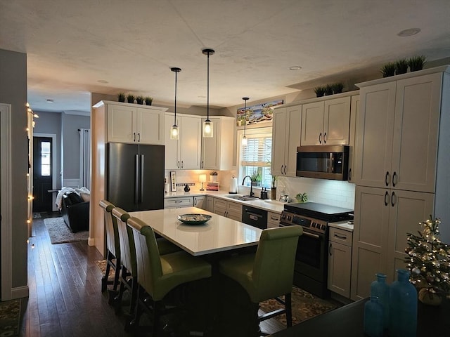 3 Panda Ct Unit 3, Milford, MA 01757 - kitchen featuring appliances with stainless steel finishes, a center island, backsplash, light countertops, and a kitchen breakfast bar