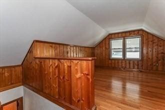 bonus room with light wood-type flooring and vaulted ceiling