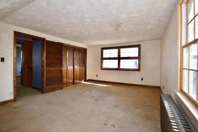 unfurnished bedroom with baseboards, a textured ceiling, and radiator heating unit