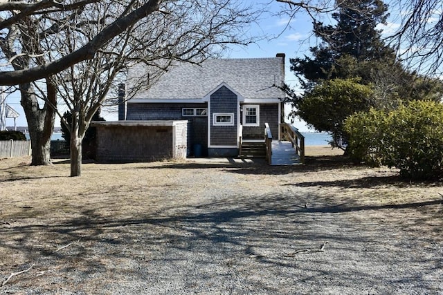 view of front of house with a chimney, a shingled roof, and fence