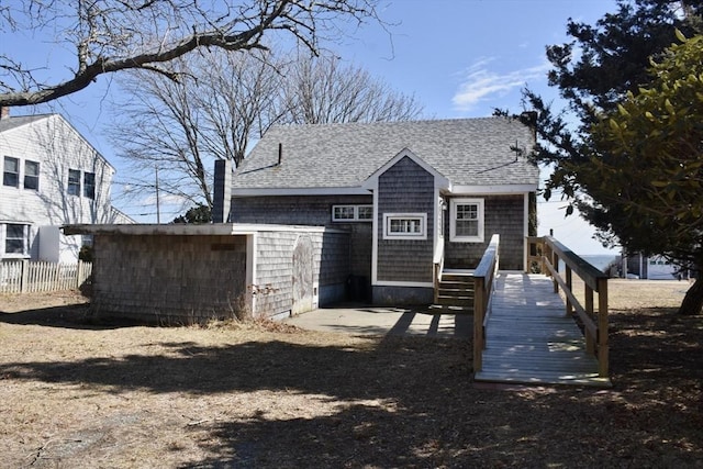 back of property with fence, a chimney, and a shingled roof