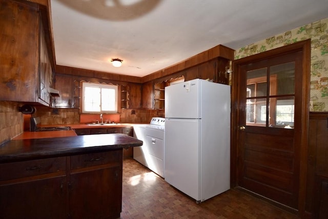 kitchen featuring a sink, washer / clothes dryer, dark countertops, and freestanding refrigerator