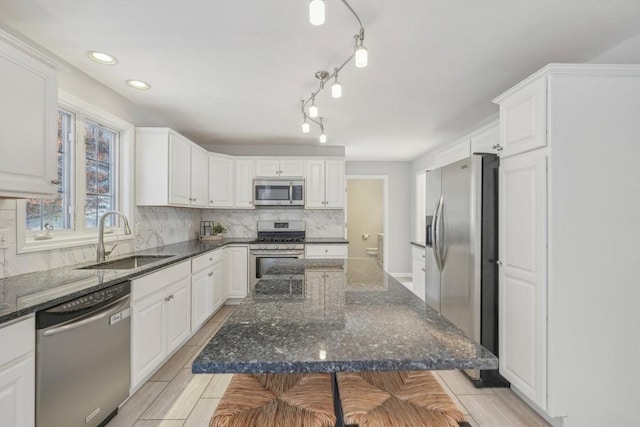 kitchen with sink, a breakfast bar area, a center island, appliances with stainless steel finishes, and white cabinets