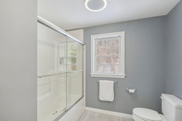 bathroom with enclosed tub / shower combo and toilet