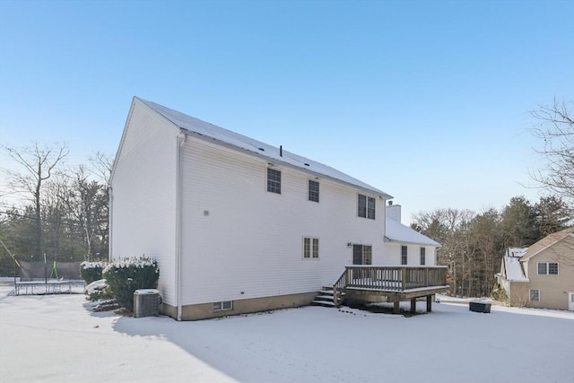 snow covered property featuring a deck, cooling unit, and a trampoline