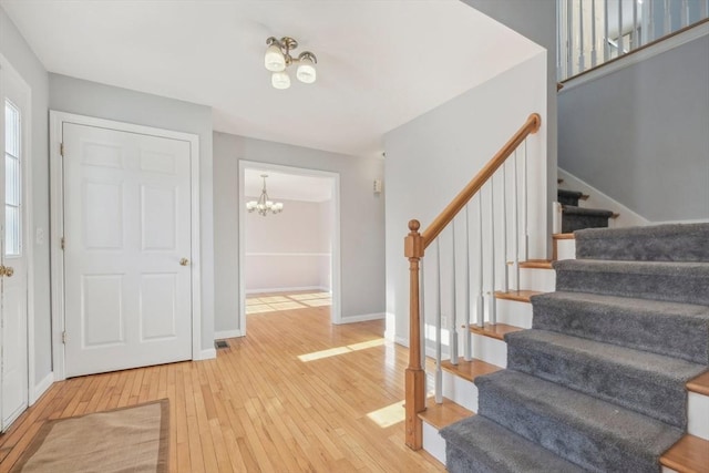 foyer entrance with wood-type flooring and an inviting chandelier